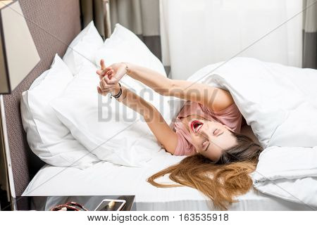 Beautiful young woman waking up in the bed at the morning. Good morning concept