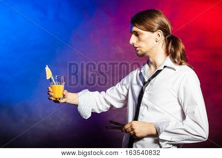 Alcohol liquor party drinking concept. Barman mixing beverages in glass. Male tapster holding drink glass.