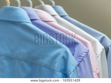 bright men's shirts hanging on hangers gray background stock photo