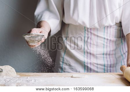 Close-up front view of two woman's hands sprinkle with flour dough for meat dumplings.