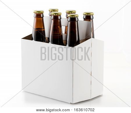 Six beer bottles in cardboard container with gold caps with corner of carrier facing camera