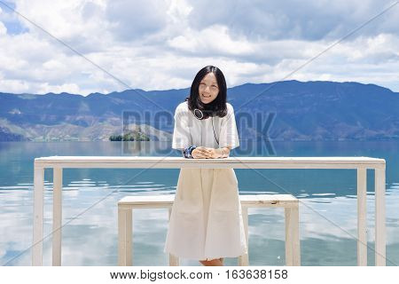 Single Chinese young girl smiles looking at camera by the bank of Lugu lake, at Daluoshui village, Lijiang, China