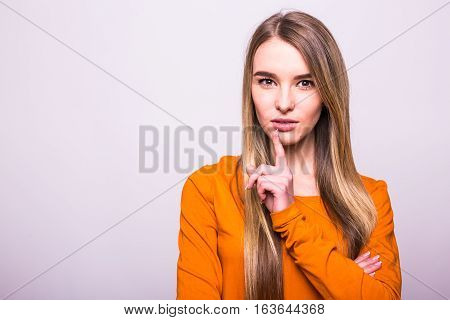 Happy Blonde Girl In Orange T-shirt With Silence Gesture On White