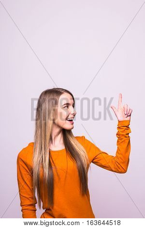 Happy Blonde Girl In Orange T-shirt Pointed Up On White