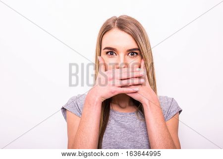 Blonde girl with hands on mouth on white