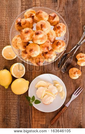 Lemon Profiteroles with custurd cream on white dish.