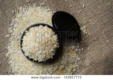 Rice in black wood container on the sack.