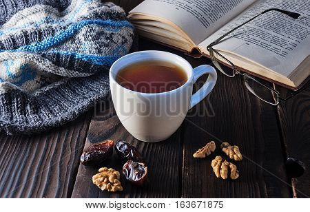 Cup of tea, book and knit cap on a wooden table