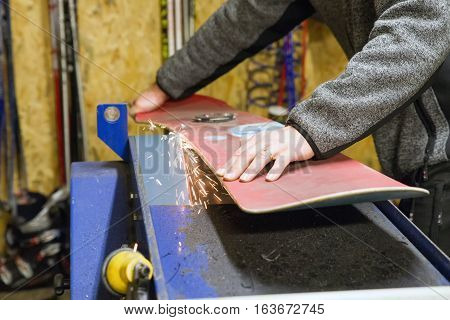 Maintenance of snowboard. Grinding and sparks. Ski service