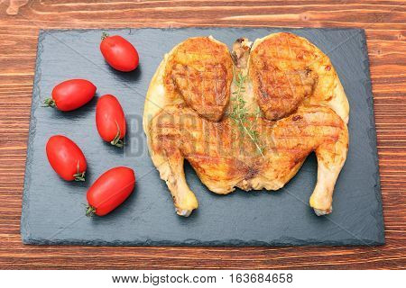 Grilled chicken Tabaka on wooden table. Georgian cuisine