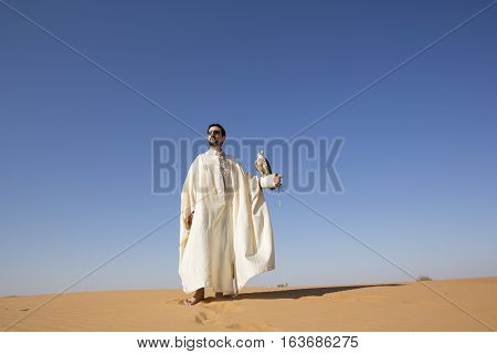 Dubai, UAE, December 3rd, 2016: Tunisian man with a seaker falcon in a desert at sunrise