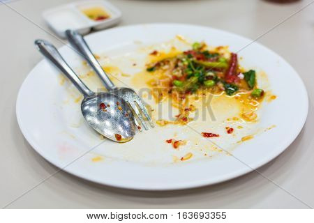 white dish with fork and spoon after eating