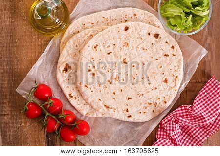 Piadina with ham and lettuce on baking paper.