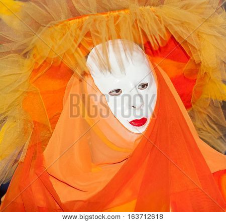 Venice Italy- February 26th 2011:Close-up image of a people wearing a specific orange costume and a mask during the Venice Carnival.
