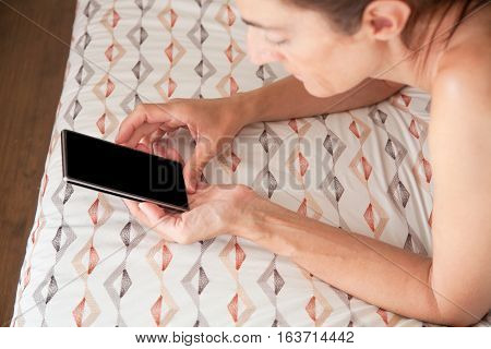 Blank Screen Of Smartphone In Woman Hands Lying On The Bed