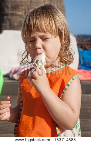 Child With Orange Bib Eating White Ice Cream
