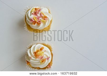 Two vanilla cupcakes on the white table