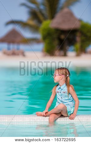 Little happy adorable girl in outdoor swimming pool