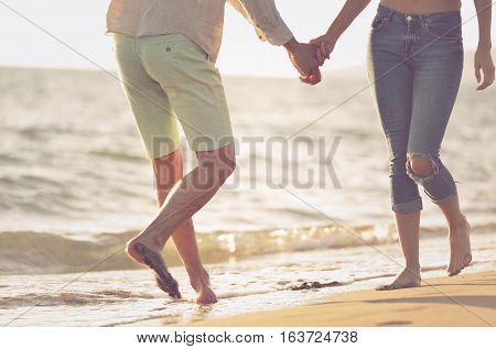 Couple walking on beach. Young happy interracial couple walking on beach smiling holding around each other