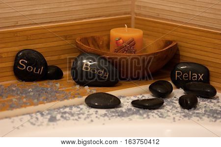 black lava stones massage and a wooden bowl with cinnamon candle with lavender salt around