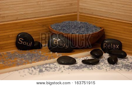 black lava stones massage and a wooden bowl with lavender salt