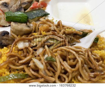 Terriyaki noodles over fried rice with mushrooms in the background