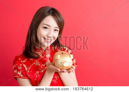 beauty woman wear cheongsam and show gold piggy bank to you in chinese new year