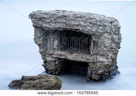Liepaja beach bunker. Brick house soft water waves and rocks. Abandoned military ruins facilities in a stormy sea. Barracks building in the Baltic sea. Liepaja Latvia Europe.