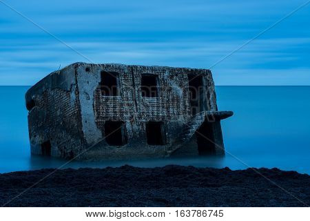 Liepaja beach bunker. Brick house soft water waves and rocks. Abandoned military ruins facilities in a stormy sea. Barracks building in the Baltic sea. Liepaja Latvia Europe.
