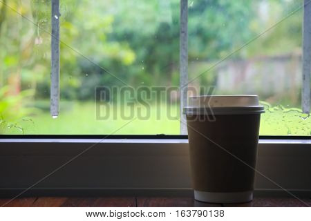Paper coffee cup placed near the window.