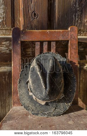 Battered old hat damaged by clothes moth on vintage background. A forgotten hat covered with spider web among the ruins of a house. Imagine the owner of this hat and tell their story.