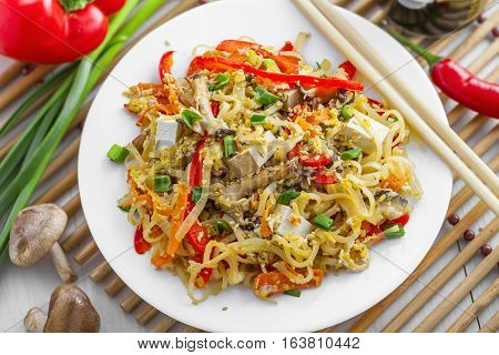 Stirred rice noodles with vegetables tofu and shiitake mushroom. Traditional Asian food. Top view close-up.
