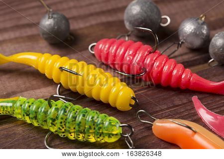 Colourful rubber fishing baitswith plummets close-up on wooden table. Selective focus.