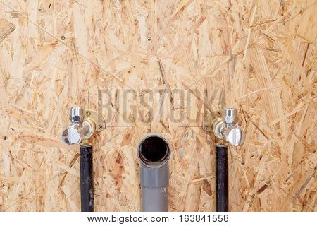 There are two water valves and a drain for a wash basin