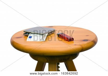 a cigarette case with a five-euro bill and a lighter on a wooden stool