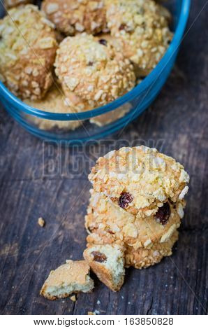 Pile of homemade cornflakes and raisins cookies on old wooden table. Freshly baked corn flake cereal cookies on rustic background. Selective Focus.