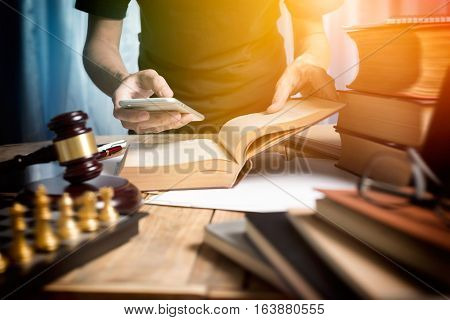 Young Man Lawyer Consulting With Teamwork By Video Conference On Mobile And Reading A Book Of Lawyer