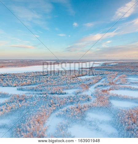 Aerial view above the snow covered tundra in time of short winter day.