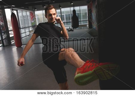Man kicked in gym on background of punching bag