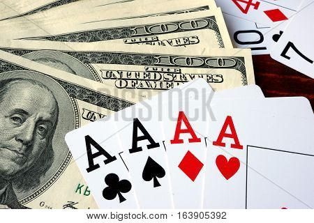 Four aces and dollars on a wooden sureface.