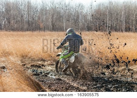KHABAROVSK RUSSIA - OCTOBER 23 2016: Enduro bike rider on a field with dry grass in autumn. The motorcycle skids and makes a lot of mud splashes