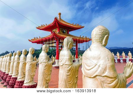 Row of golden Buddha statues with blurred temple in the background