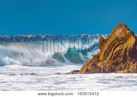 Waves breaking on the rocks with blue sky