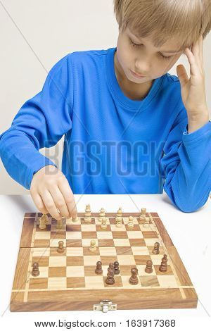 Little caucasian boy playing chess and making next move. Game education lifestyle concept