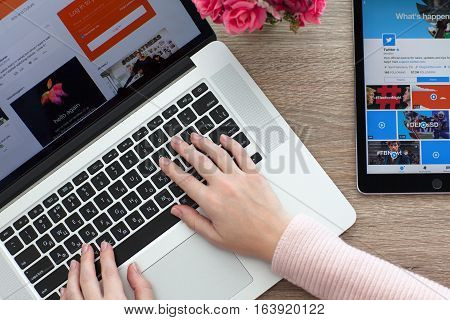 Woman with MacBook and iPad Pro with social networking service Twitter on the screen. MacBook and iPad Pro was created and developed by the Apple inc.