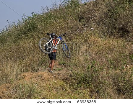 Mountain biking in Nepal. Young woman nountain biker carrying her bike. Biking near Kathmandu Nepal.