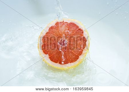 Water flowing on a juicy grapefruit closeup
