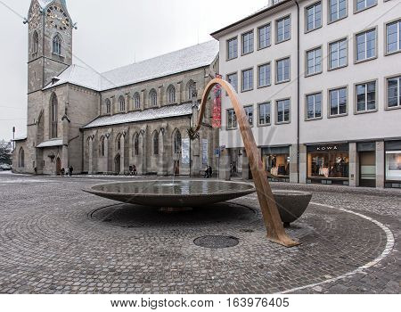 Zurich, Switzerland - 3 January, 2017: fountain on Munsterhof square, the Fraumunster Cathedral in the background. The diameter of the fountain is six meters, its height is almost four meters.