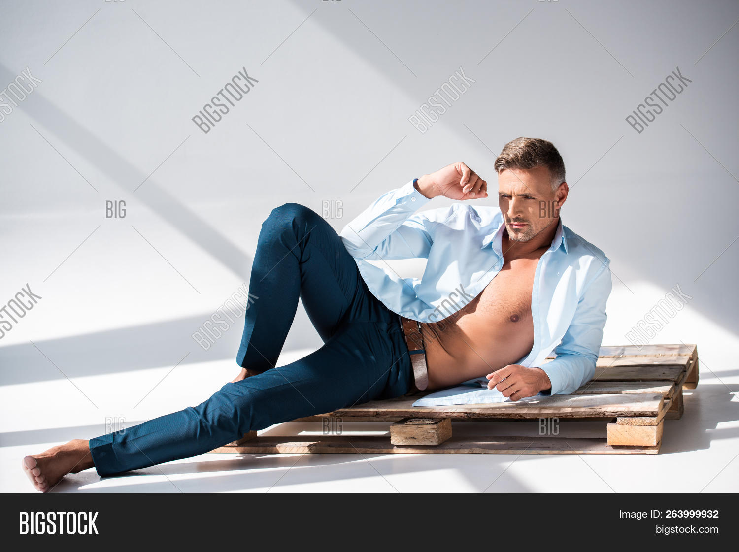 В задумчивой позе с расстегнутым жилетом. Задумчивый мужчина. Мужчина в расстегнутой рубашке сидит. Задумчивый бизнесмен. Мужчина боком.