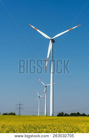 Wind Energy Plants In A Field Of Blooming Oilseed Rape Seen In Germany